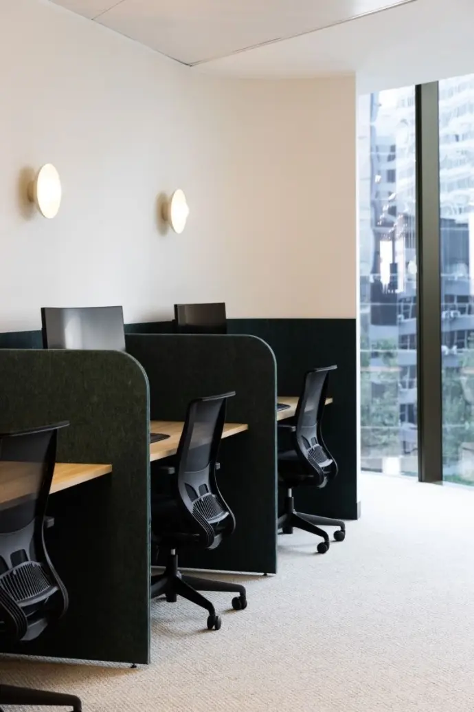 Green fabric acoustic dividers creating four-person work pod