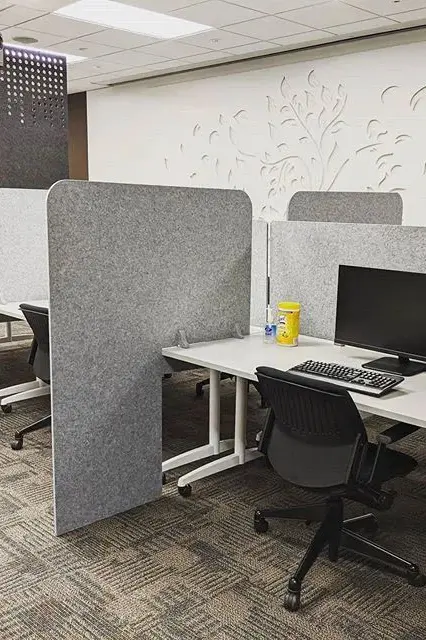 Green freestanding acoustic room divider in modern office with plant